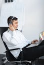 A Man Talking on a Headset while Using a Laptop