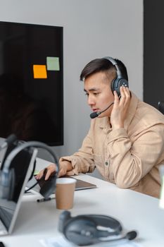 Focused call center agent using headset and laptop in modern office setting.