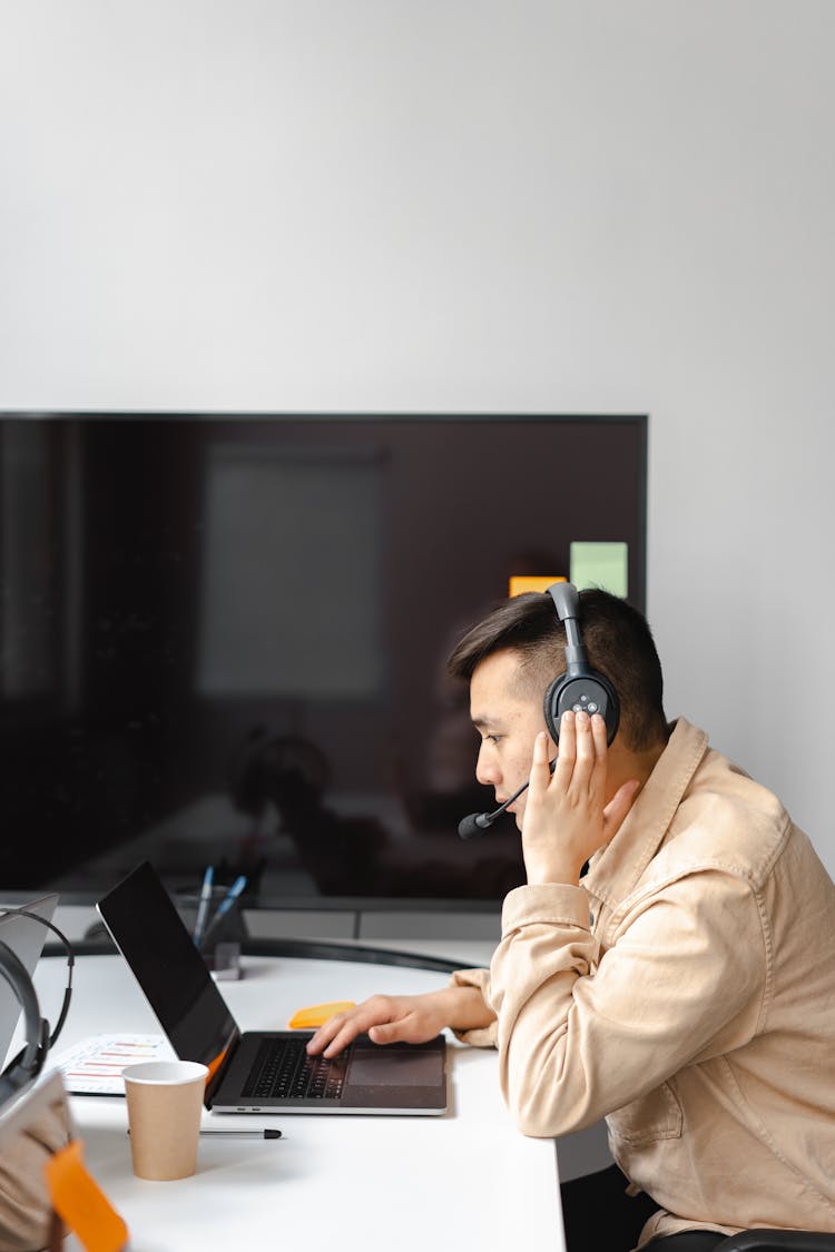 Man Wearing His Headphone In Front Of His Laptop