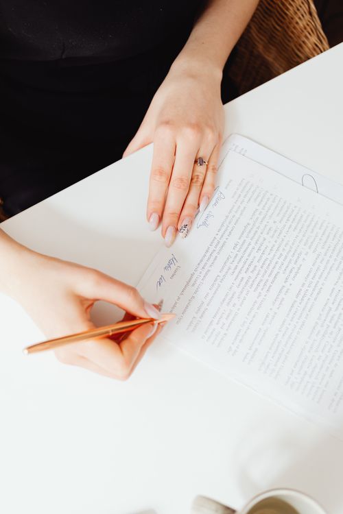 Free A woman's hands holding a pen over a paper document. Indoor writing scene. Stock Photo