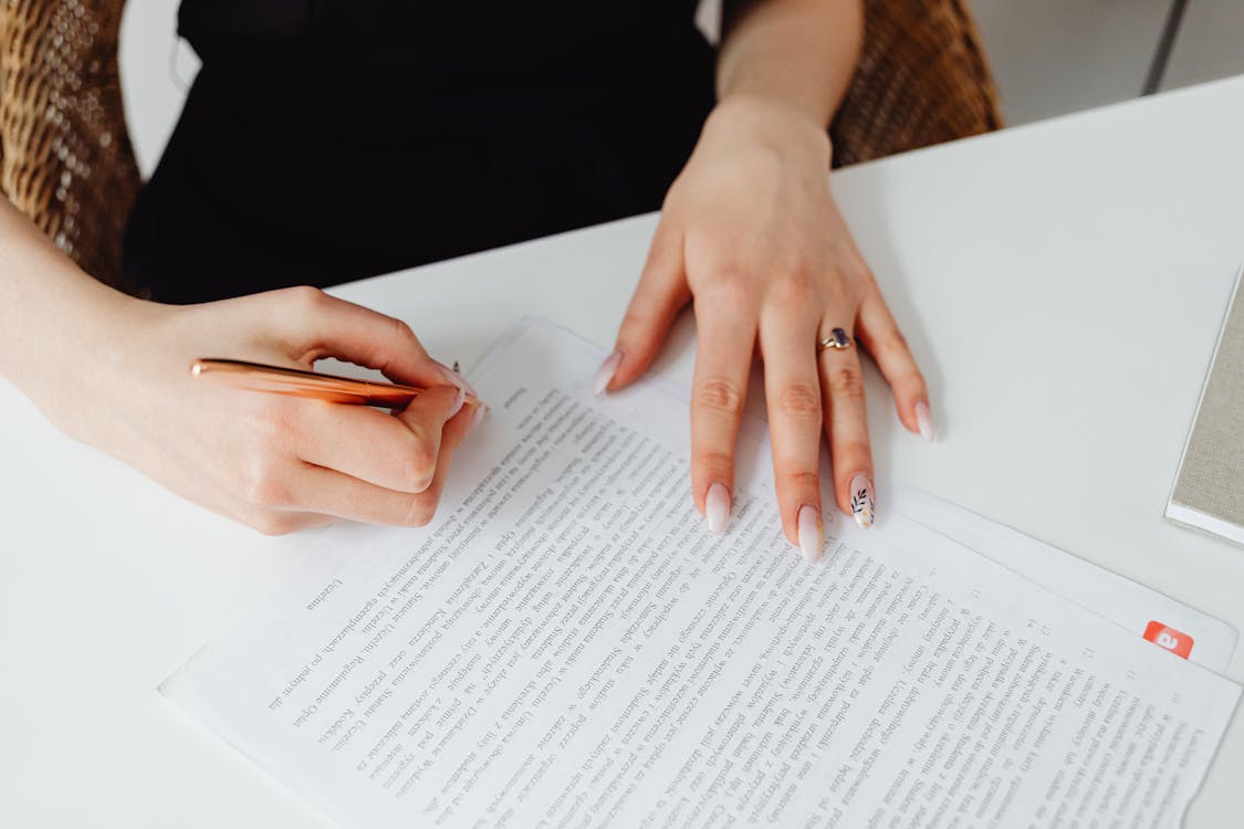 Free Person Holding Pen Writing on a Document Stock Photo