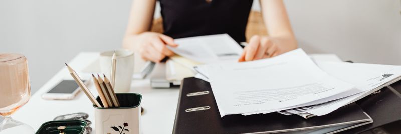 A woman at a desk working with binders and documents, featuring essential office supplies.