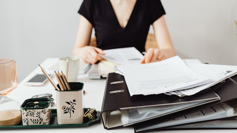 A woman at a desk working with binders and documents, featuring essential office supplies.