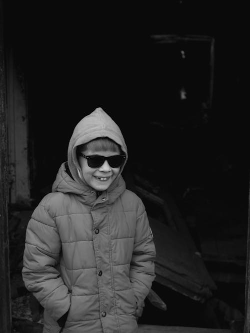Free Grayscale Photo of a Boy Wearing His Sunglasses and Winter Coat Stock Photo
