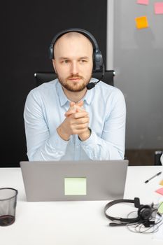Business professional in call center with headset and laptop, working indoors.