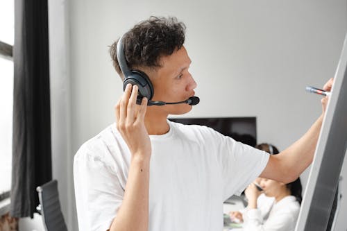 Man Wearing Headset Writing on Whiteboard