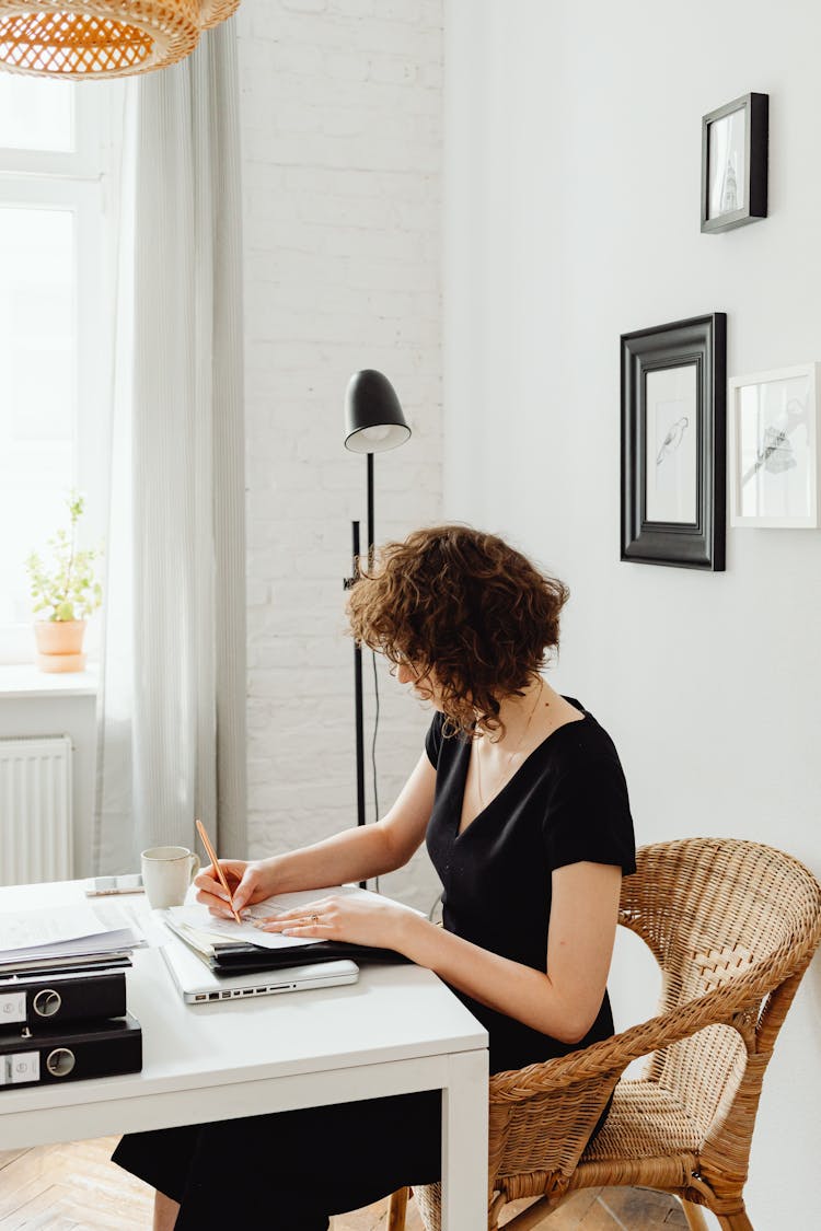 Woman Sitting By Table And Writing