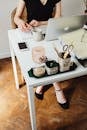 Person in Black Leather Shoes Sitting on White Wooden Table