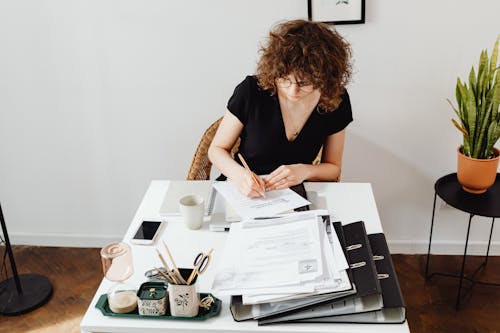 Woman in a Black Shirt Writing on a Paper