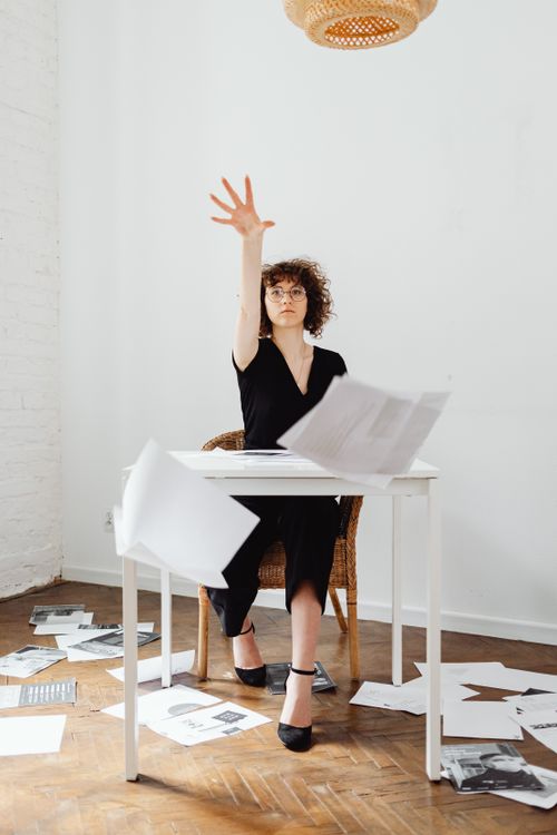 Free Woman throwing papers in modern office space, expressing creativity. Stock Photo