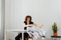 Woman in Black Shirt and White Pants Sitting on Brown Wooden Seat