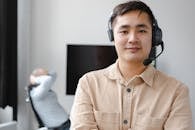 Smiling Man in Brown Button Up Shirt Wearing Black Headphones