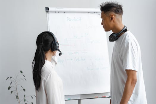 Two call center employees discussing a project while wearing headsets.