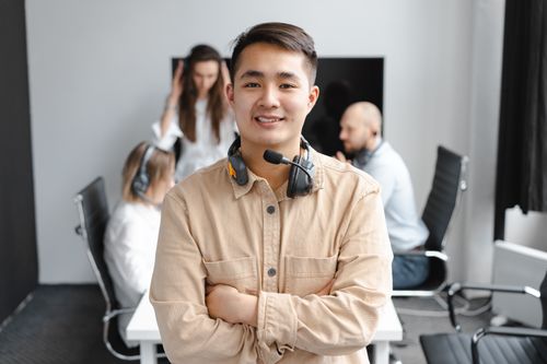 Free Smiling call center agent with headset in office setting, showcasing teamwork and communication. Stock Photo
