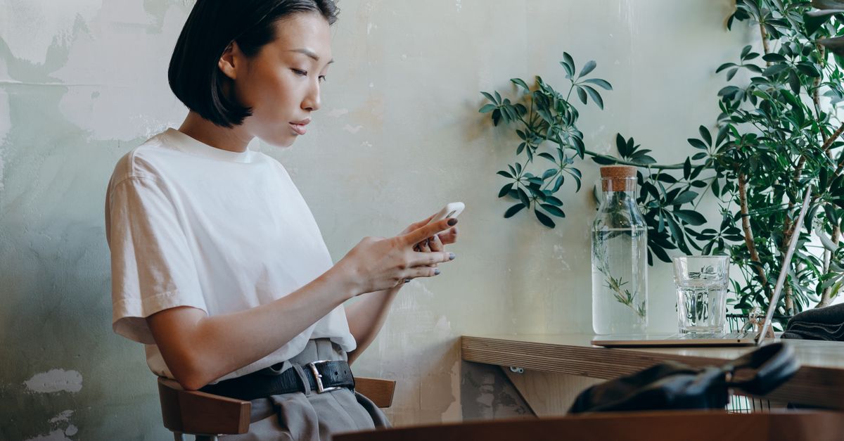 Woman in a café using a smartphone, reflecting a casual work environment.