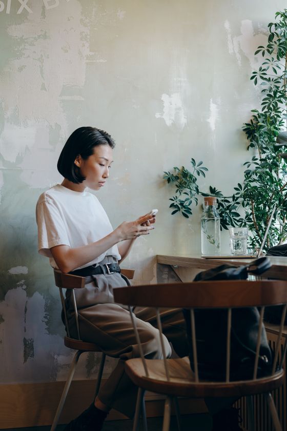 Woman checking her phone at a cafe table &mdash; photo by Mikhail Nilov on Pexels