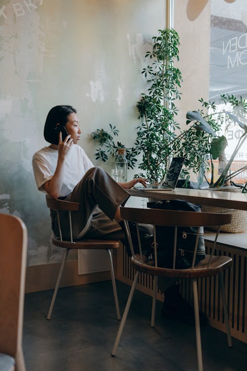 Businesswoman in White Shirt Sitting on Chair while Having Phone Call