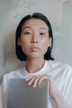 Portrait of a serene woman holding a laptop, showcasing elegance and modernity.