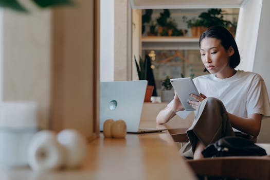 Asian woman using a tablet for remote work in a modern indoor setting.