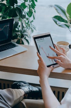 Close-up of hands using a tablet for stock market analysis in a modern office setting.