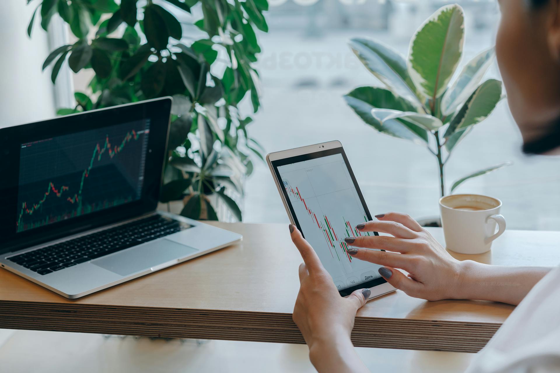 A professional analyzes stock market graphs on a tablet, symbolizing modern finance and remote work.