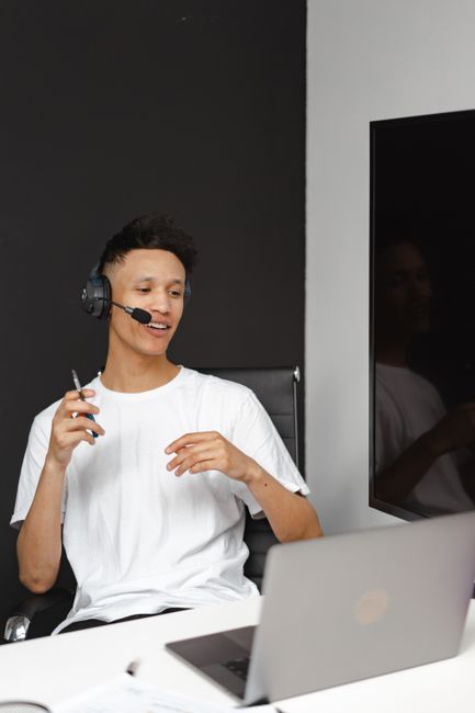 Professional engaged in remote work using laptop and headset in modern office setting. Professional engaged in remote work using laptop and headset in modern office setting.