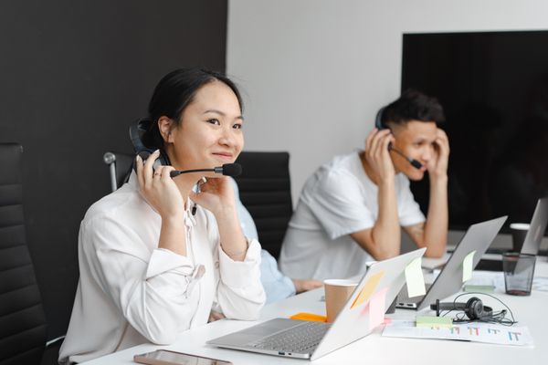 Support agents working on laptops with headsets — photo by Mikhail Nilov on Pexels