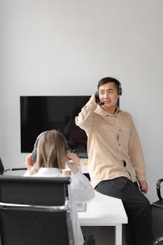 Two colleagues with headsets engage in conversation, working in a modern call center environment.