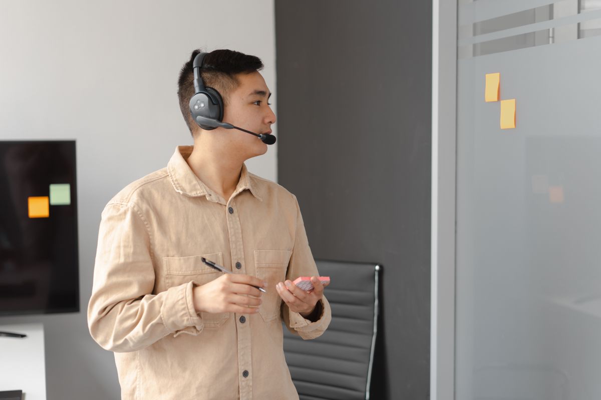 Professional man working in call center holding pen and smartphone