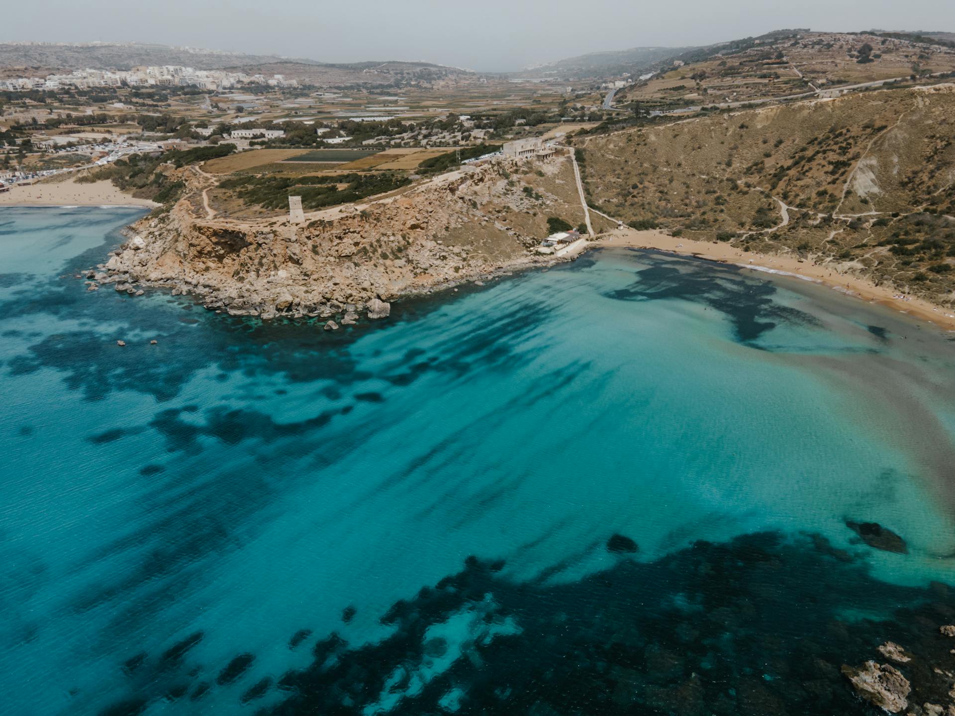 Scenic aerial shot of the coastal view in Mgarr, Malta featuring blue waters and rocky landscapes.