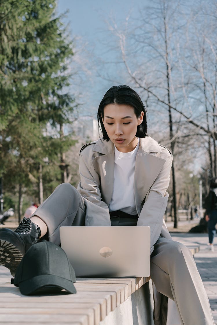 Woman Sitting On The Bench While Using Her Laptop