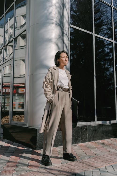 Woman in Gray Trench Coat Standing Near a Building