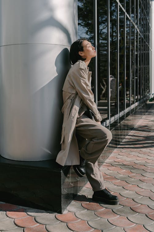 Woman in Beige Coat Leaning on Wall