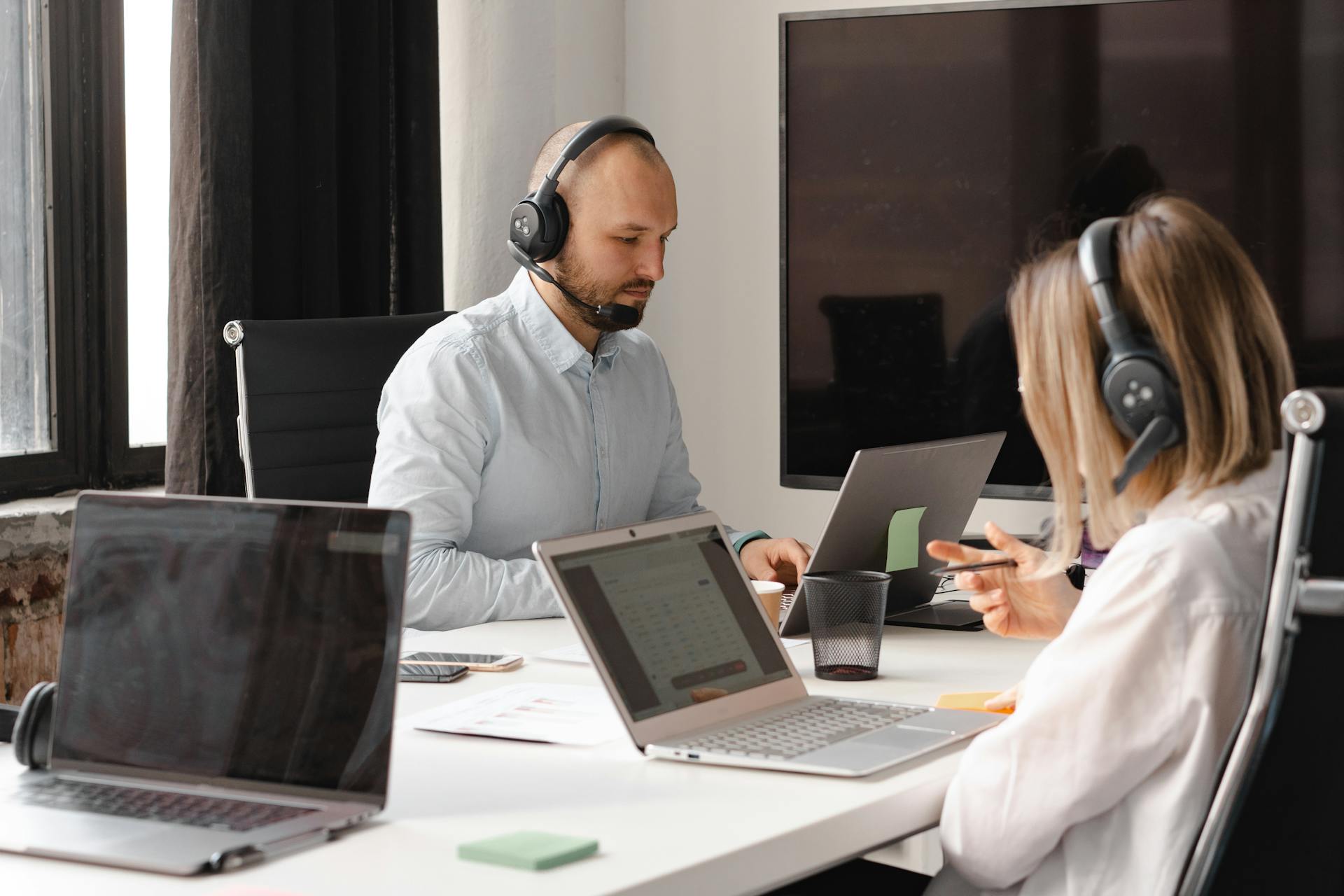 Customer support agents working together with laptops and headsets in an office setting.