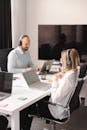 Man and Woman Wearing Headphones while Working in the Office