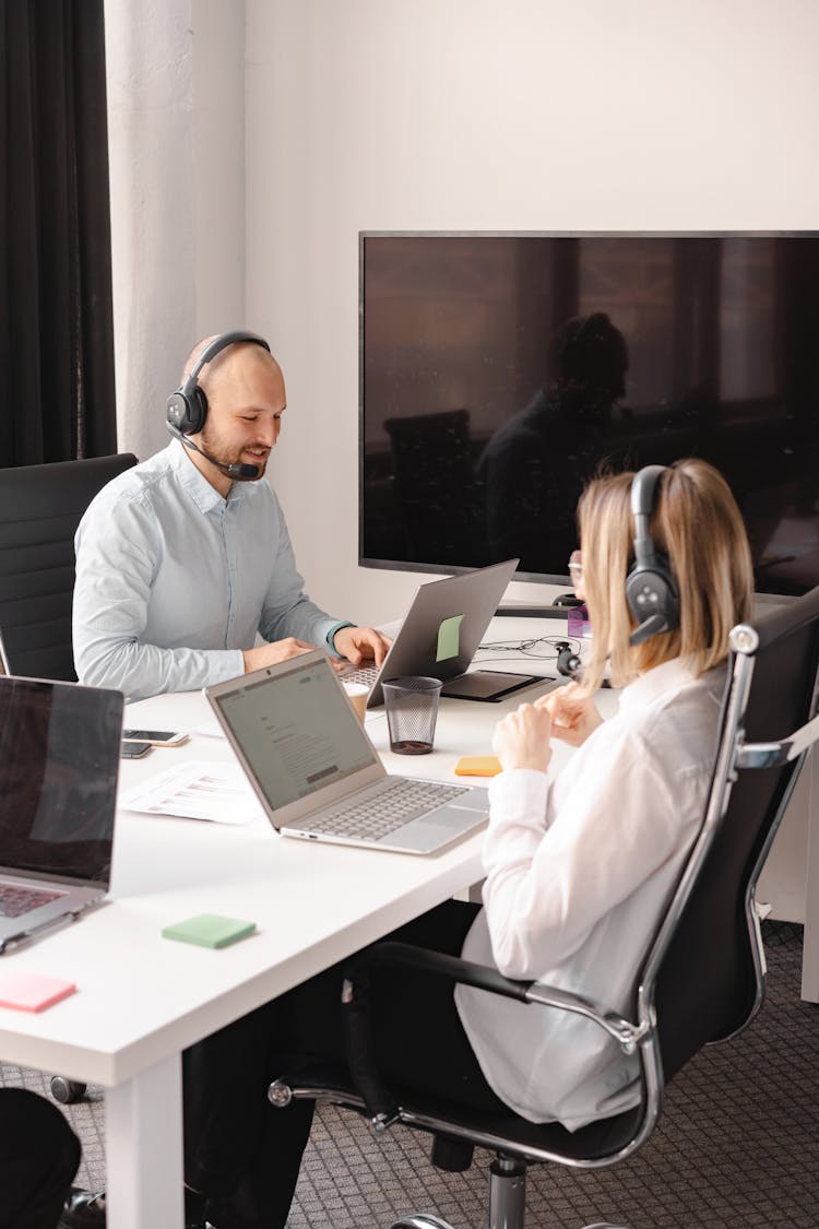 Man And Woman Wearing Headphones While Working In The Office