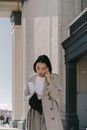 Woman in White Coat Standing Near White Concrete Building