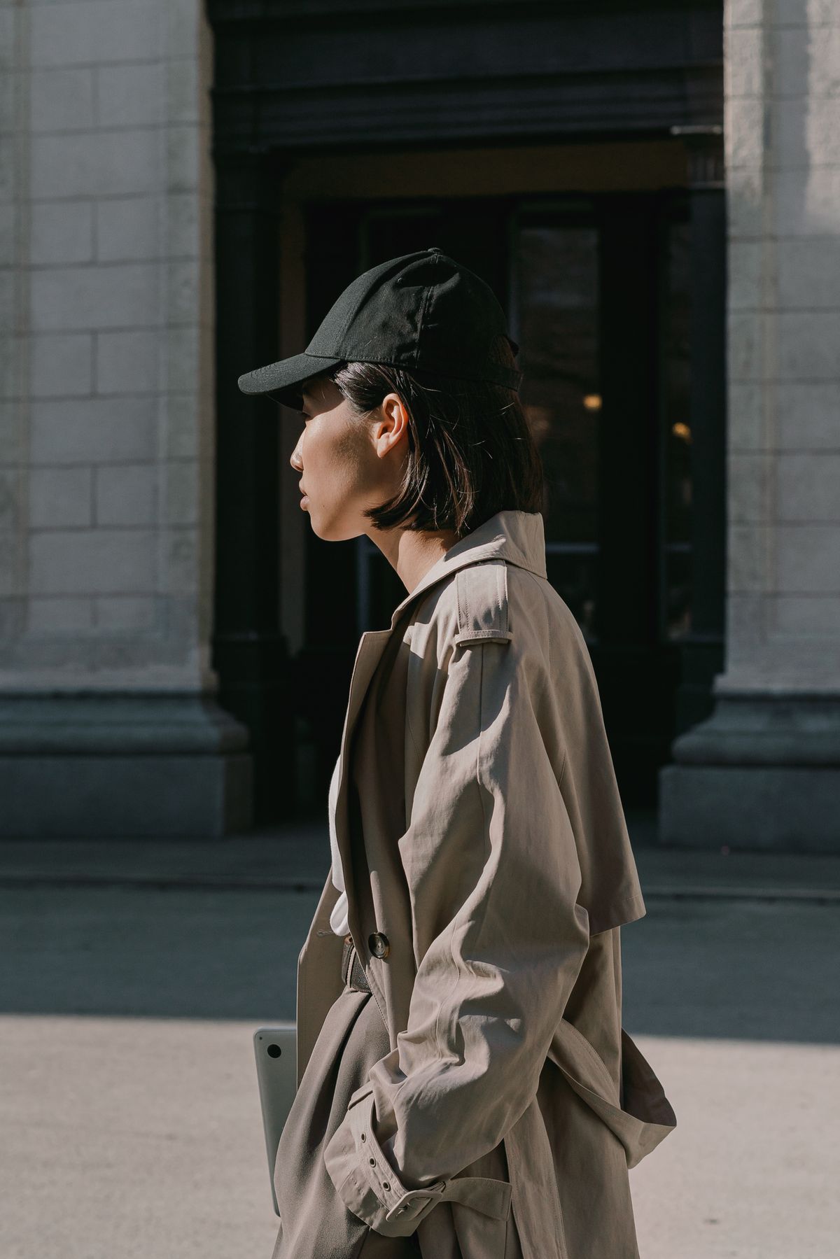 A woman in a coat wearing a black cap — the modern cropped trench, styled down