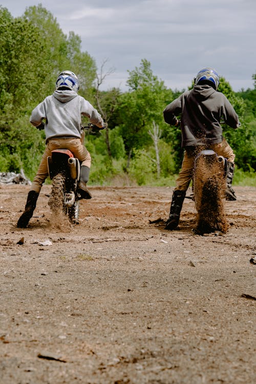 Back View of Two People Driving Dirt Bikes on Dirt Road