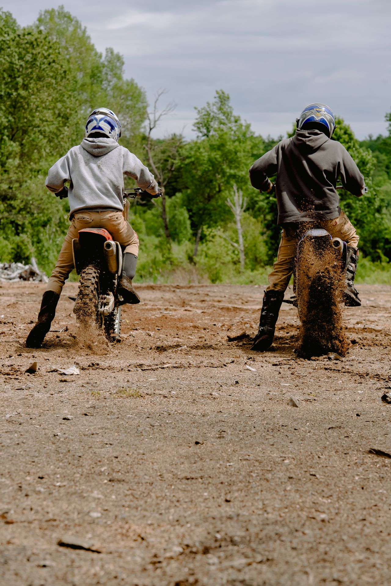 Two riders on dirt bikes on a dirt road