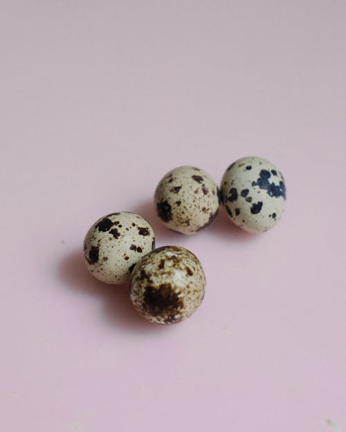 Close-Up Photo of Quail Eggs on a Pink Surface