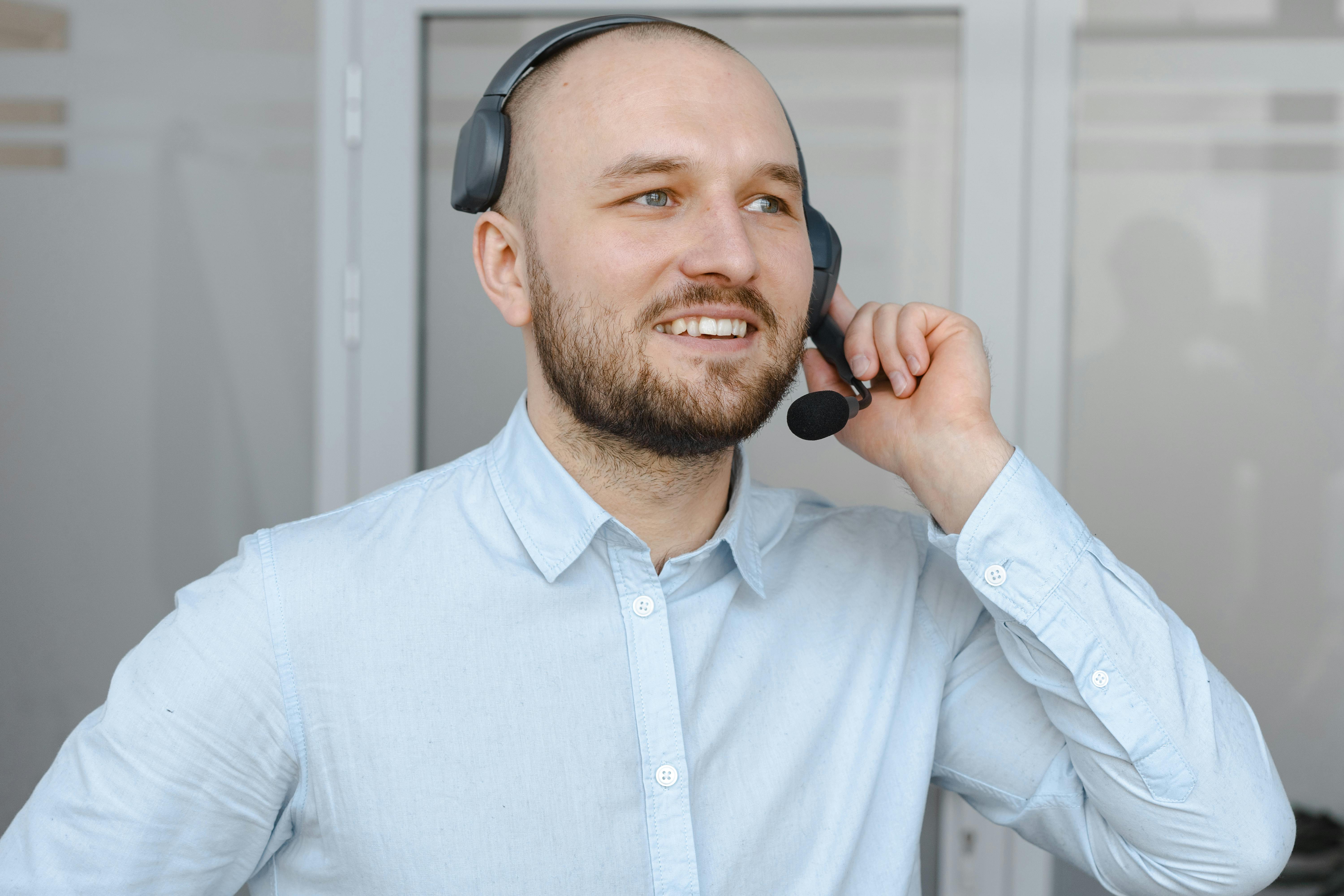 smiling man in blue long sleeves wearing a black headset