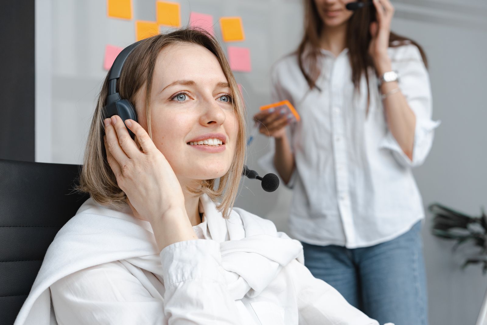 A smiling customer support agent wearing a headset assisting a caller