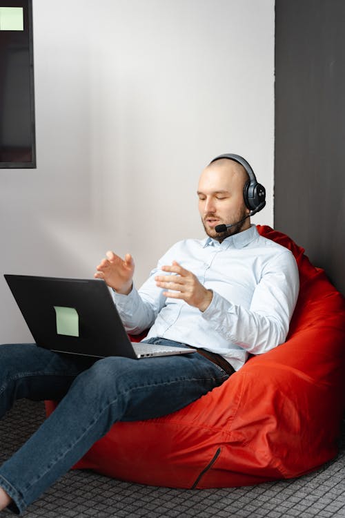 Man Sitting on Red Chair while Working in a Call Center