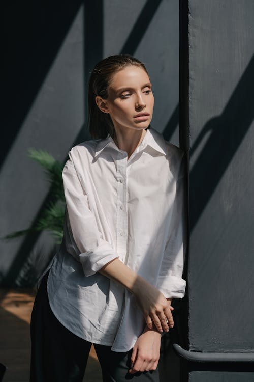 Free Woman in Dress Shirt Leaning on Black Wall while Looking to Her Left Stock Photo