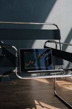 An empty designer chair with a tablet showing a stock market graph, creating a modern business atmosphere.