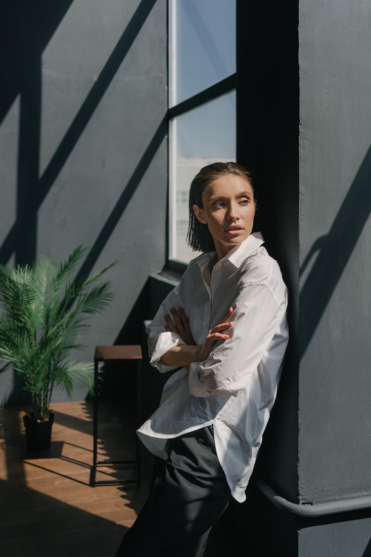 Confident Woman In White Dress Shirt Leaning On Black Wall