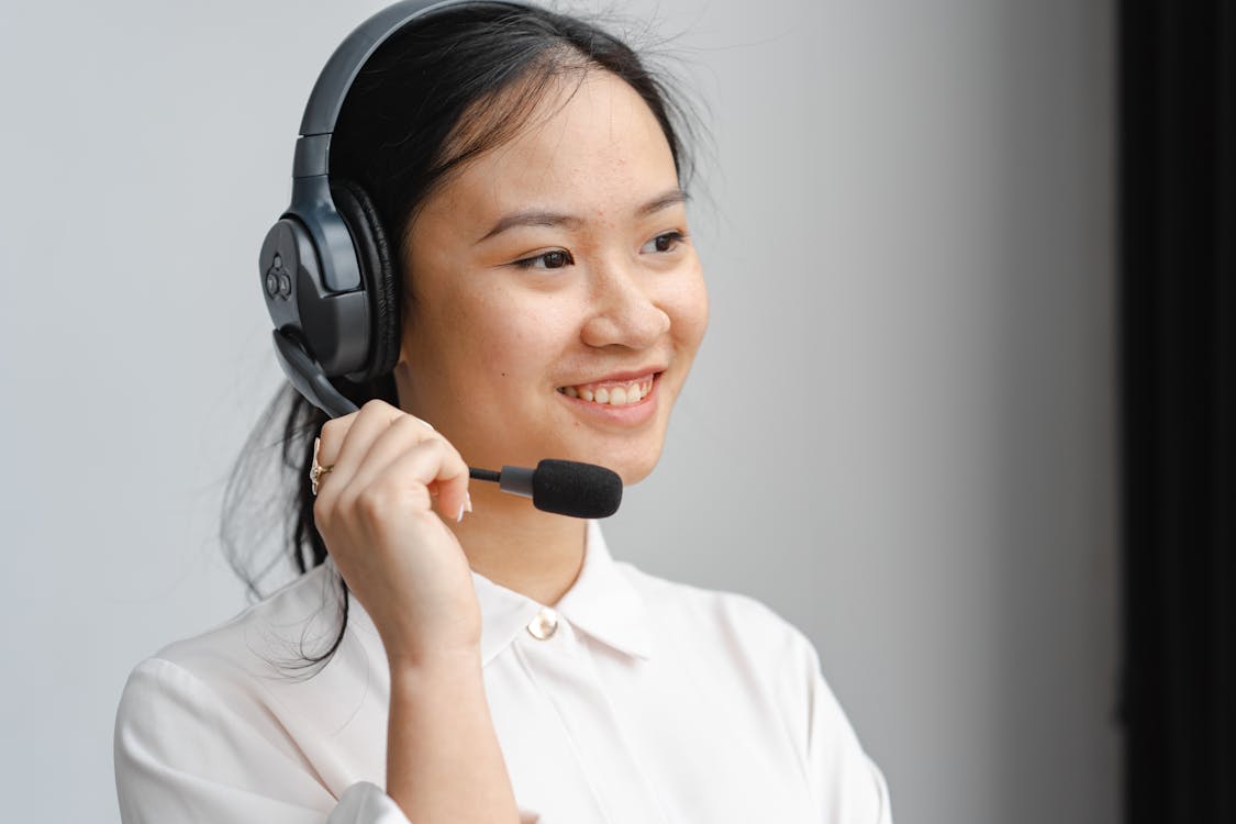 Close-Up Photo of a Woman Holding the Microphone of Her Black Headset