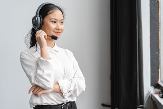 Professional Asian woman with headset providing customer support in an office setting.
