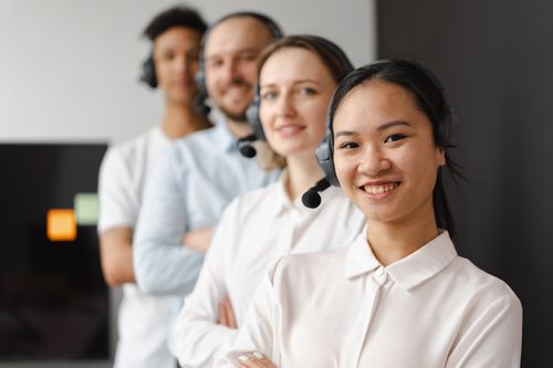 Free A diverse group of smiling call center agents with headsets, standing together indoors. Stock Photo